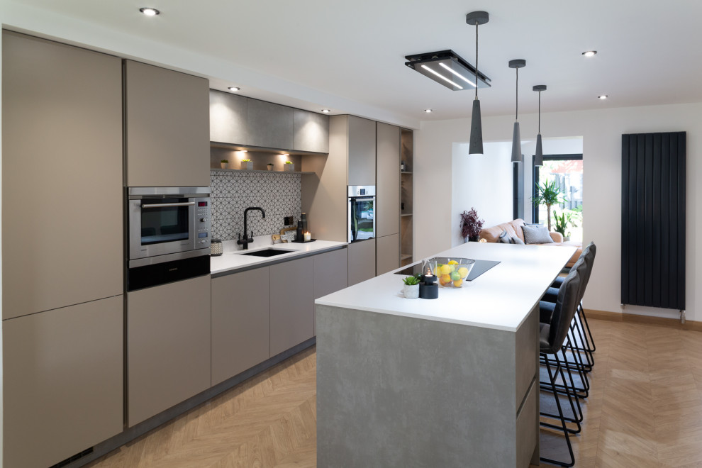 Foto di un cucina con isola centrale minimalista con ante lisce, ante beige, top in cemento, paraspruzzi multicolore e elettrodomestici in acciaio inossidabile