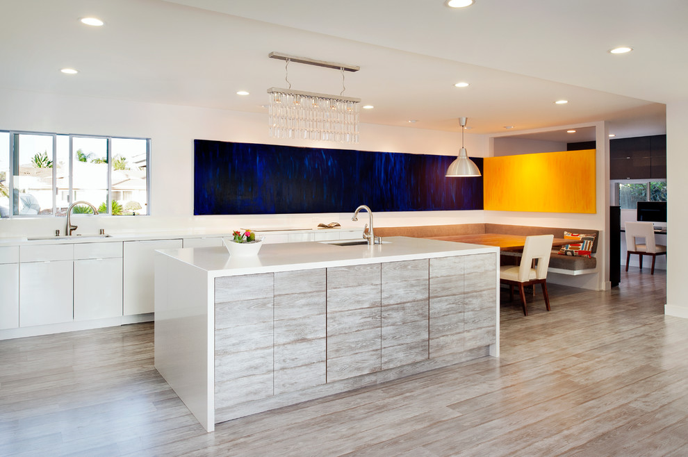 This is an example of a large contemporary l-shaped open plan kitchen in San Diego with an undermount sink, flat-panel cabinets, white cabinets, with island, quartz benchtops, white splashback, stone slab splashback, stainless steel appliances and laminate floors.