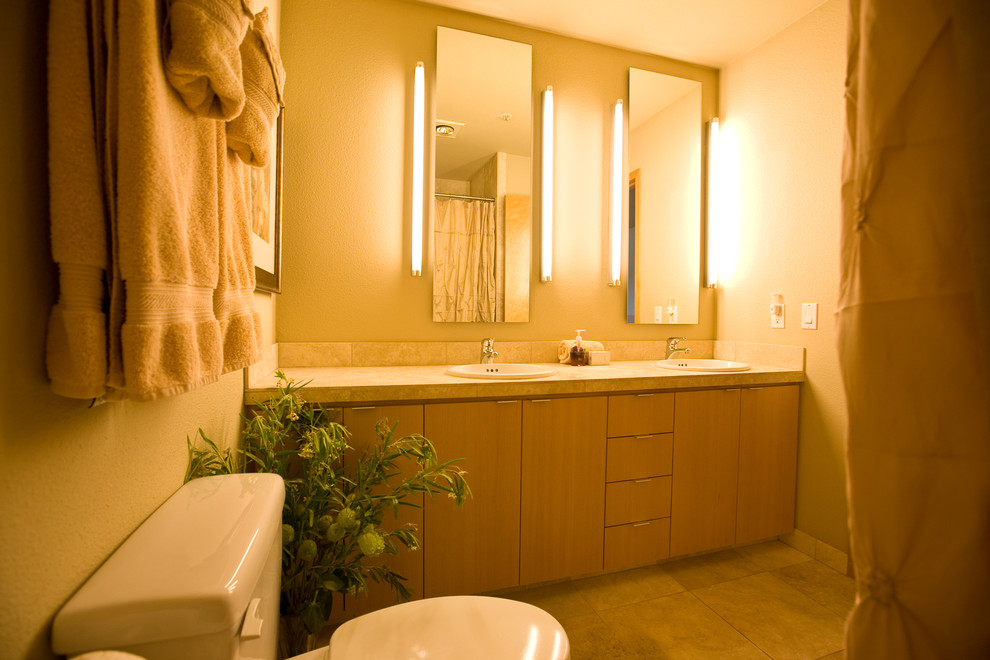 Photo of a mid-sized contemporary master bathroom in Portland with flat-panel cabinets, light wood cabinets, a two-piece toilet, beige walls, ceramic floors, an undermount sink and solid surface benchtops.