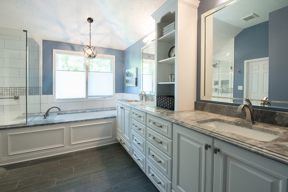 Large country master bathroom in Indianapolis with raised-panel cabinets, white cabinets, an undermount tub, a corner shower, gray tile, ceramic tile, blue walls, ceramic floors, a drop-in sink and quartzite benchtops.
