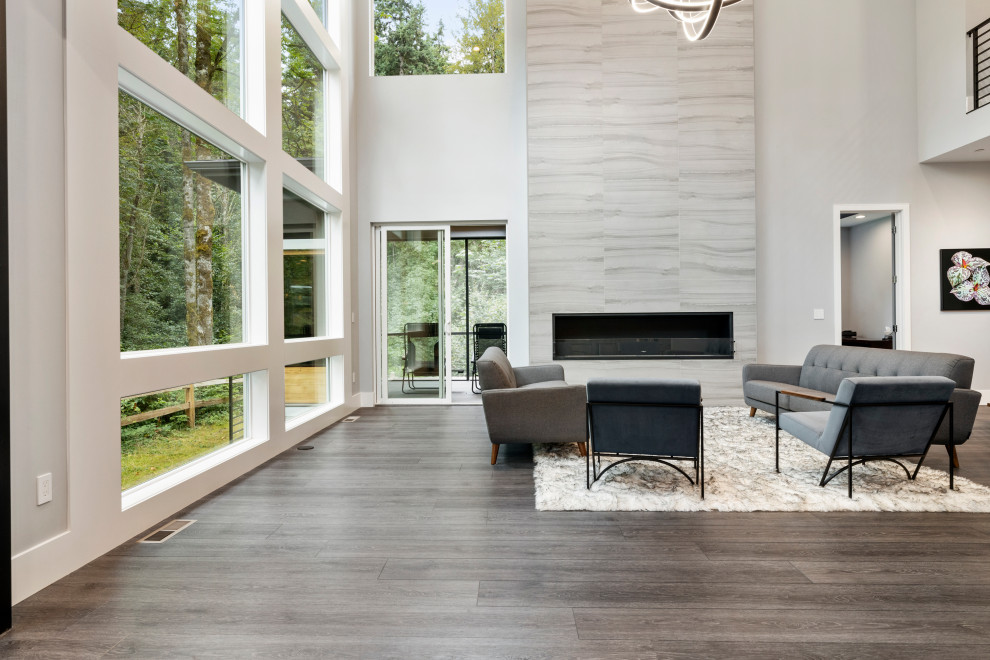 Photo of a large modern formal open plan living room in Seattle with grey walls, vinyl flooring, a standard fireplace, a stone fireplace surround, grey floors and a vaulted ceiling.