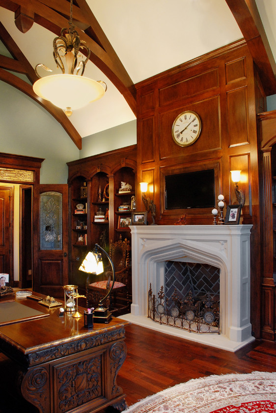 Traditional study room in Kansas City with blue walls, medium hardwood floors, a standard fireplace, a stone fireplace surround and a freestanding desk.