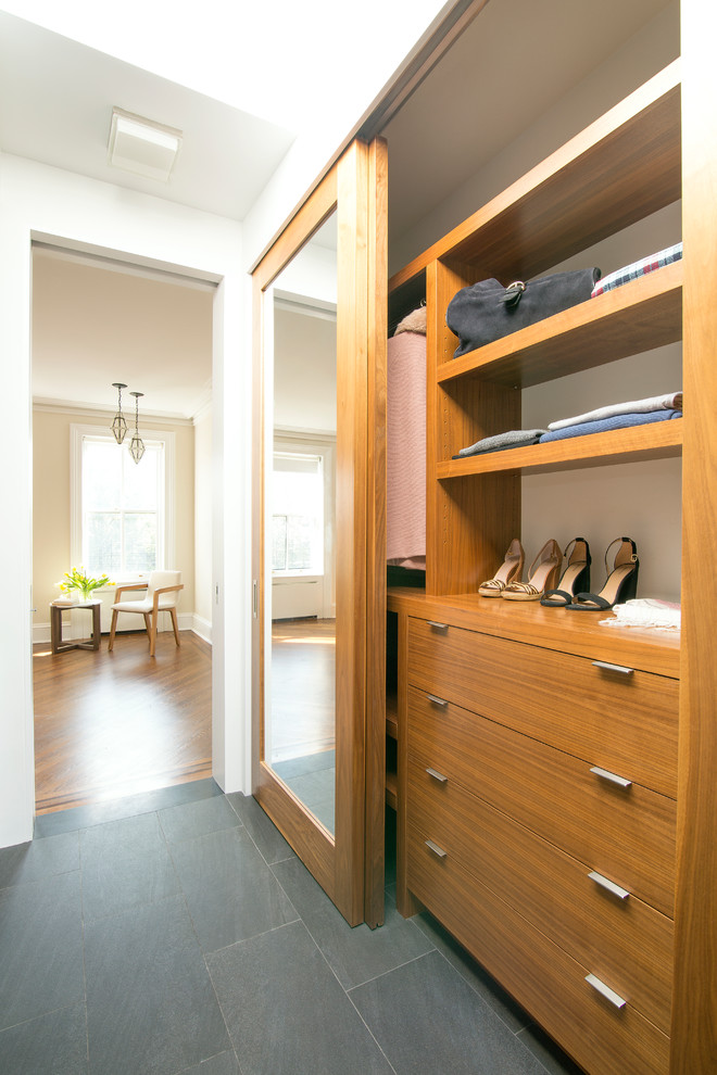 This is an example of a mid-sized contemporary gender-neutral built-in wardrobe in New York with flat-panel cabinets, medium wood cabinets and porcelain floors.