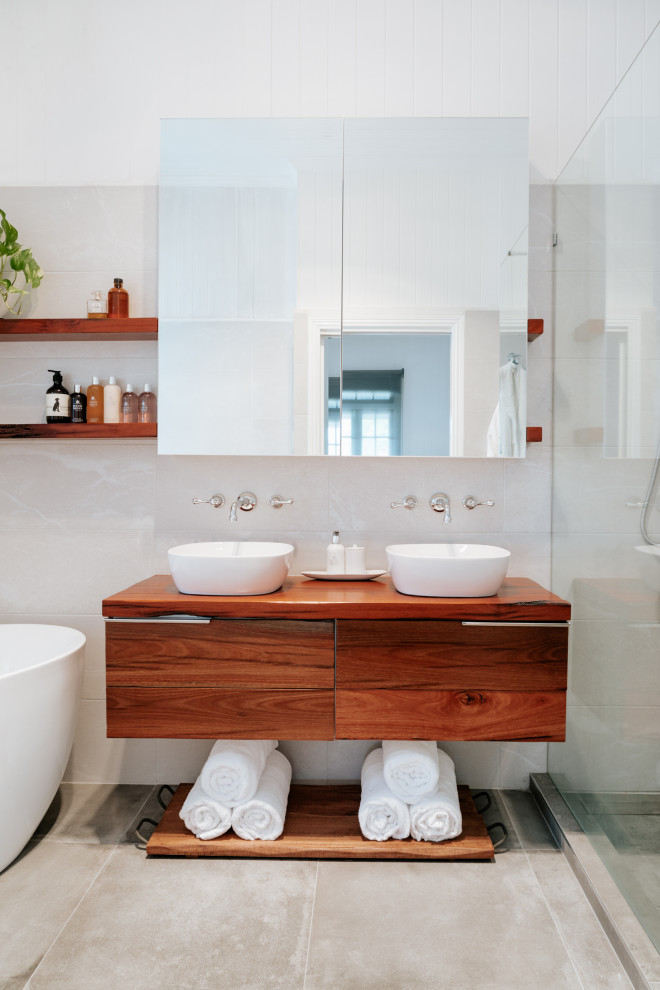 Inspiration for an industrial master bathroom in Brisbane with medium wood cabinets, a freestanding tub, gray tile, ceramic tile, cement tiles and wood benchtops.
