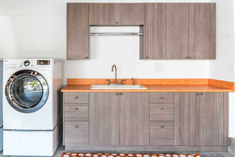 This is an example of a small contemporary utility room in San Francisco with a single-bowl sink, flat-panel cabinets, grey cabinets, laminate benchtops, medium hardwood floors and a side-by-side washer and dryer.