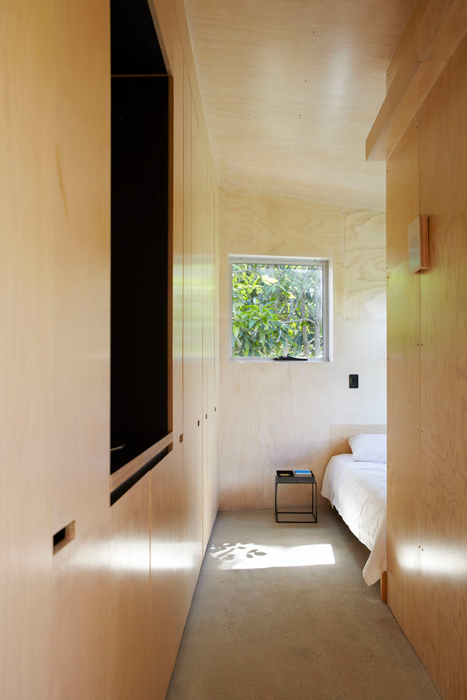 Small industrial master bedroom in Sunshine Coast with beige walls, concrete floors and grey floor.