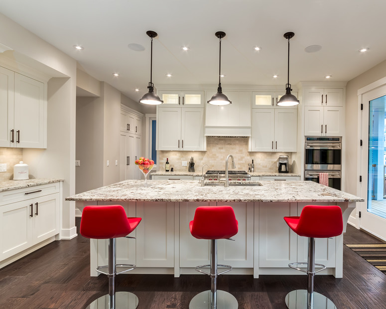 Large transitional single-wall dark wood floor and brown floor enclosed kitchen photo in Calgary with an undermount sink, shaker cabinets, white cabinets, granite countertops, beige backsplash, porcelain backsplash, stainless steel appliances and an island