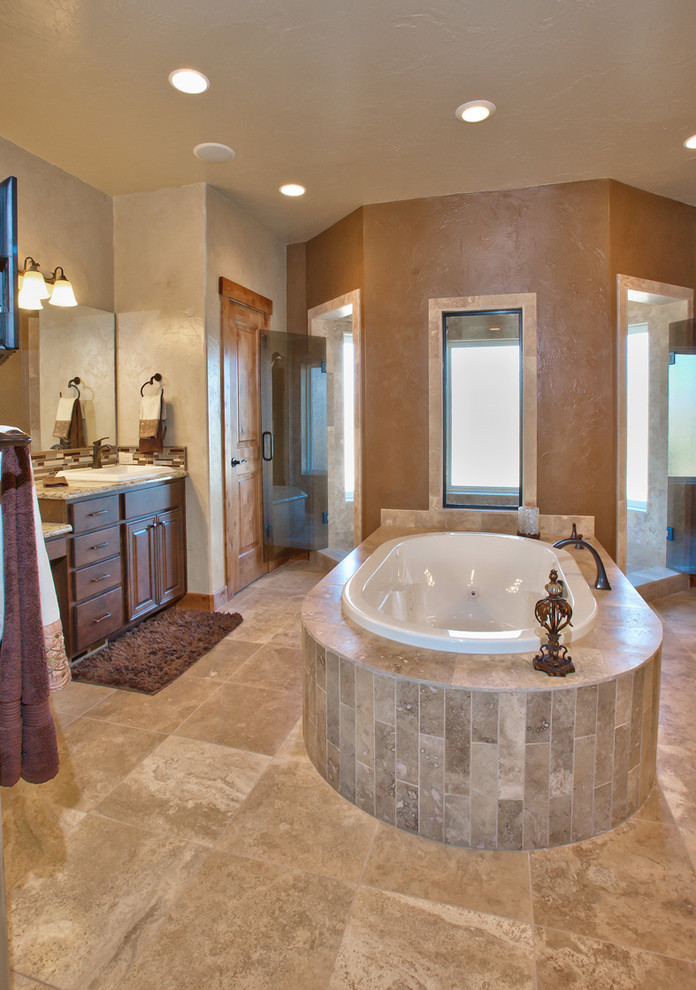Example of a transitional master beige tile and stone tile travertine floor freestanding bathtub design in Denver with a vessel sink, raised-panel cabinets, medium tone wood cabinets, granite countertops and beige walls