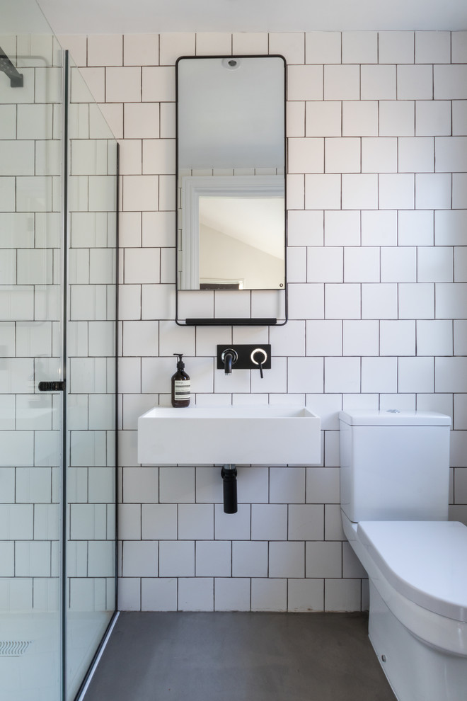 Design ideas for a transitional 3/4 bathroom in London with an alcove shower, white tile, white walls and concrete floors.