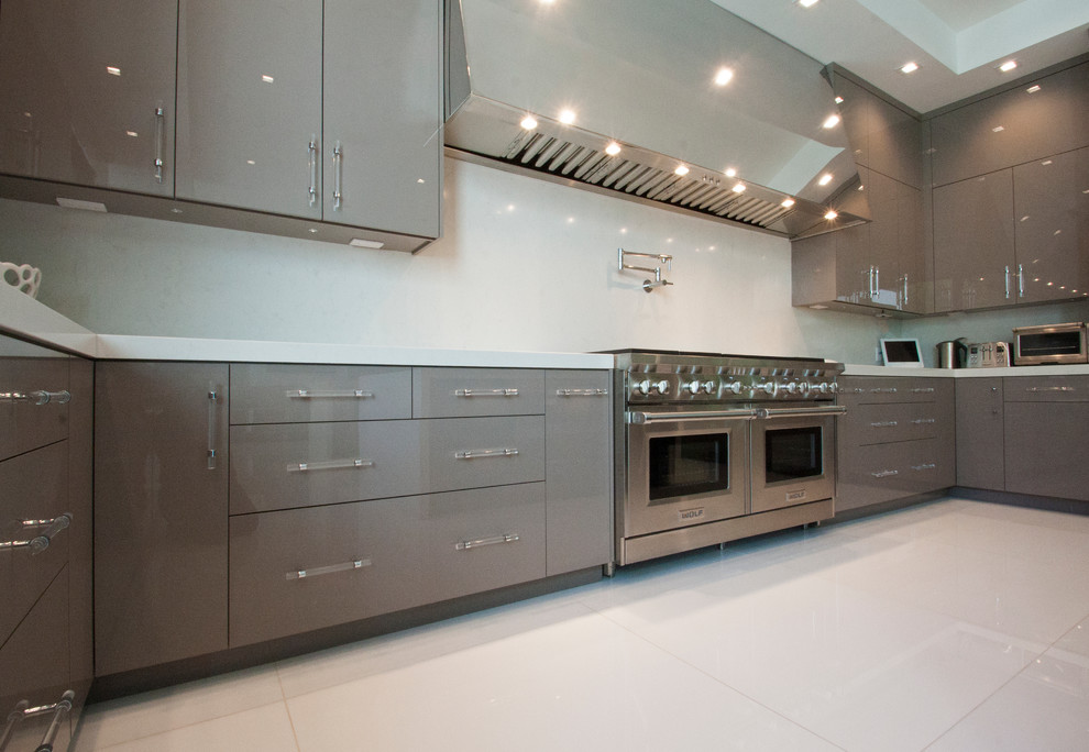 This is an example of an expansive modern u-shaped eat-in kitchen in Los Angeles with an undermount sink, flat-panel cabinets, beige cabinets, solid surface benchtops, stainless steel appliances, marble floors and multiple islands.