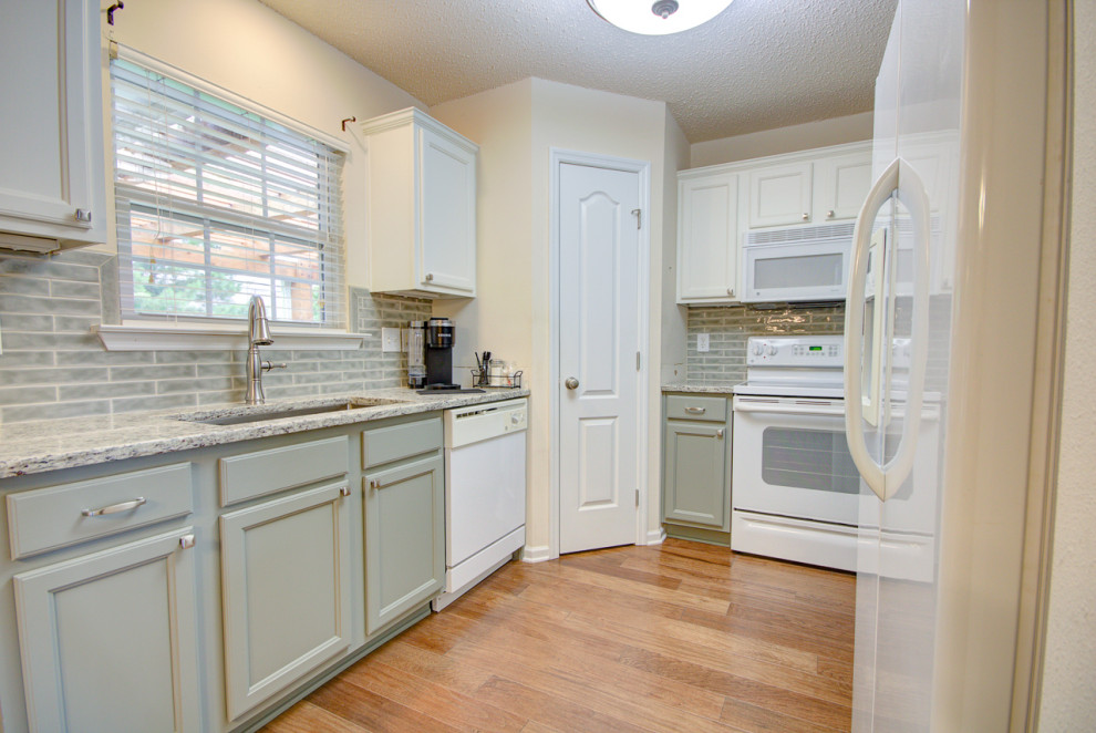 Inspiration for a mid-sized transitional u-shaped medium tone wood floor and brown floor eat-in kitchen remodel with an undermount sink, shaker cabinets, green cabinets, granite countertops, green backsplash, ceramic backsplash, white appliances, no island and multicolored countertops