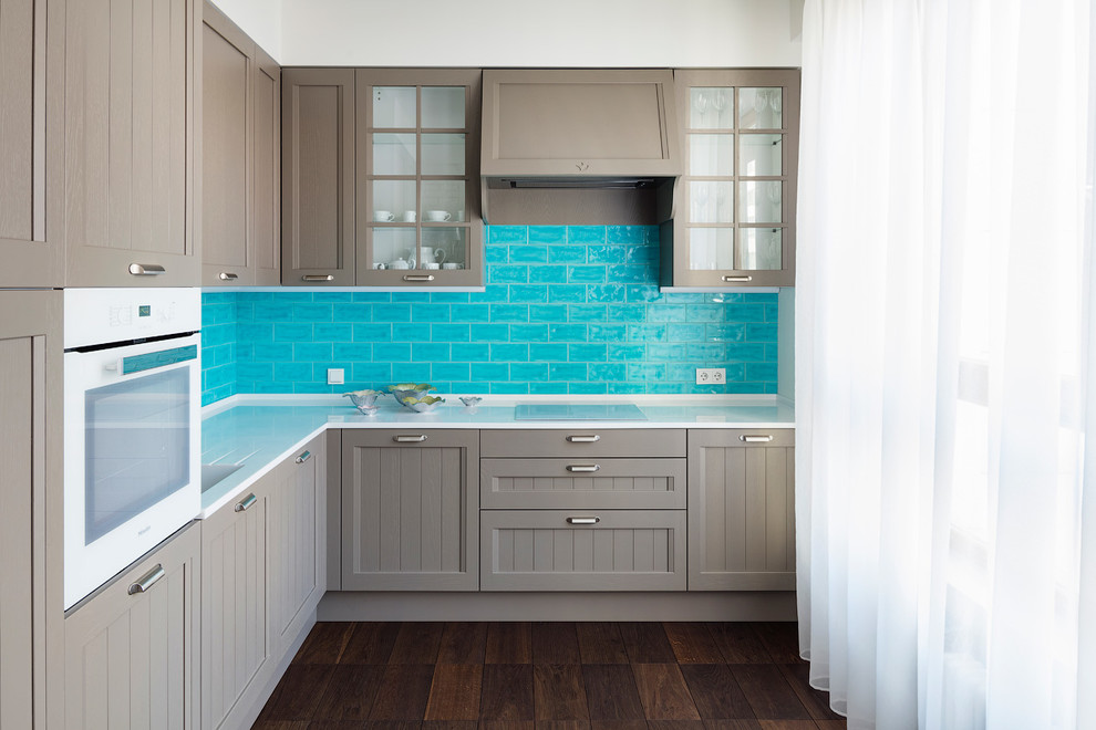 This is an example of a contemporary l-shaped kitchen in Moscow with an integrated sink, grey cabinets, blue splashback, white appliances, brown floor, shaker cabinets, subway tile splashback, dark hardwood floors and no island.