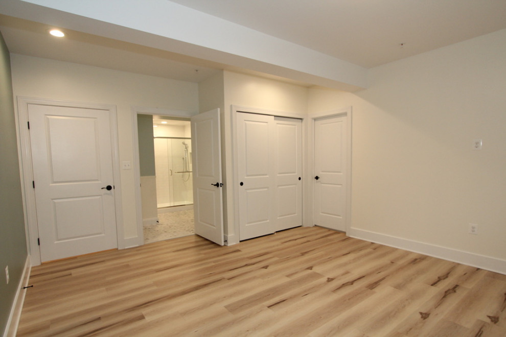 Aménagement d'un grand sous-sol classique avec un mur beige, un sol en vinyl et un sol beige.
