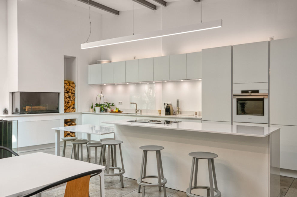 Contemporary galley kitchen in Bordeaux with an undermount sink, flat-panel cabinets, white cabinets, white appliances, with island, grey floor, white benchtop and vaulted.