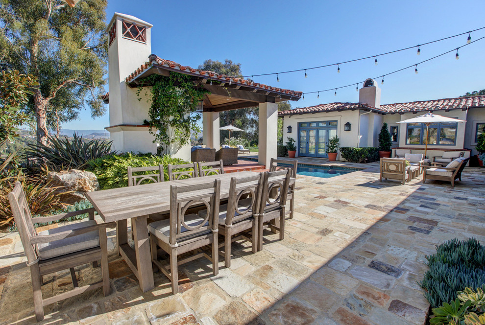 Photo of a large mediterranean backyard patio in Orange County with with fireplace, natural stone pavers and a gazebo/cabana.
