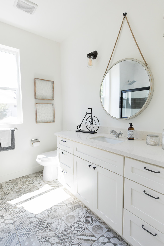 Mid-sized country kids bathroom in Phoenix with shaker cabinets, white cabinets, a drop-in tub, a shower/bathtub combo, a two-piece toilet, white walls, cement tiles, an undermount sink, engineered quartz benchtops, multi-coloured floor, a sliding shower screen and white benchtops.