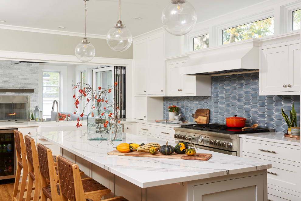 Design ideas for a large transitional kitchen in Minneapolis with a farmhouse sink, recessed-panel cabinets, white cabinets, quartz benchtops, blue splashback, ceramic splashback, stainless steel appliances, light hardwood floors, with island, yellow floor and white benchtop.
