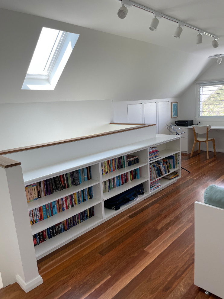 Photo of a large contemporary study room in Wollongong with white walls, light hardwood floors, a built-in desk, brown floor and vaulted.