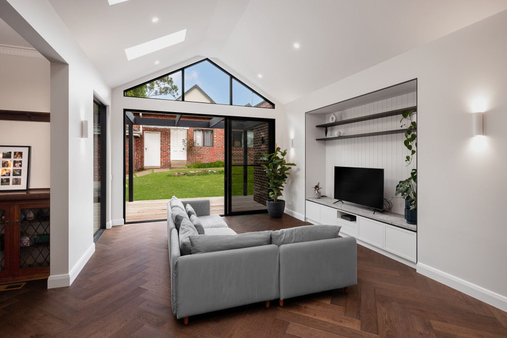 Inspiration for a large contemporary open plan living room in Melbourne with white walls, dark hardwood flooring, a built-in media unit, brown floors, a vaulted ceiling and tongue and groove walls.