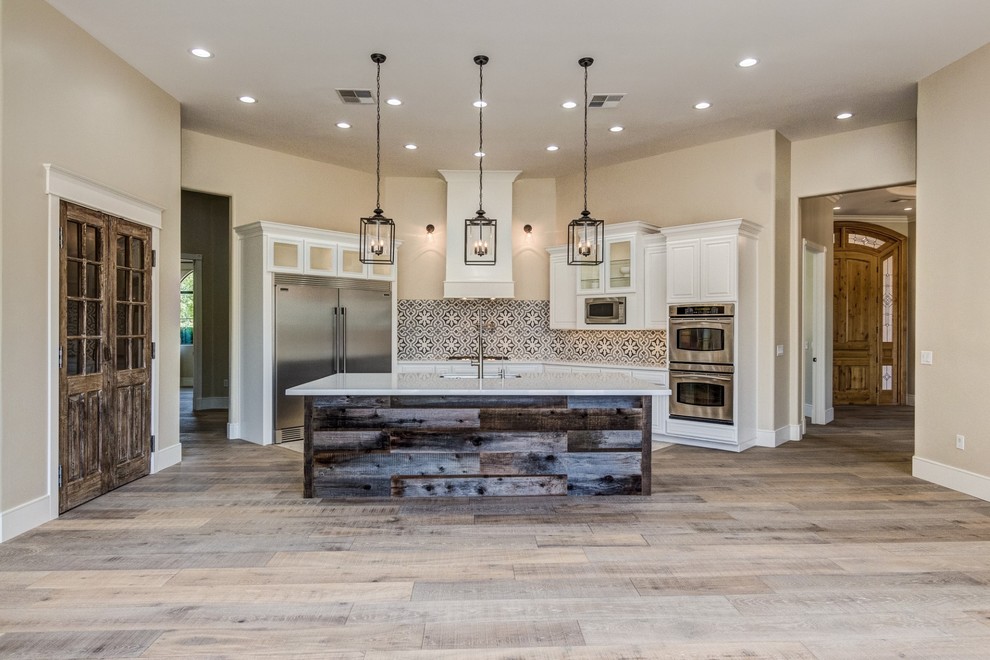 Eat-in kitchen - mid-sized transitional l-shaped light wood floor and beige floor eat-in kitchen idea in Phoenix with an undermount sink, raised-panel cabinets, white cabinets, quartz countertops, multicolored backsplash, cement tile backsplash, stainless steel appliances, an island and white countertops