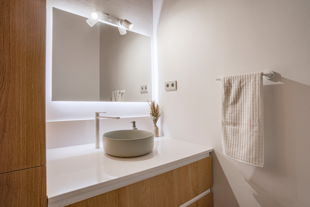 Inspiration for a small traditional powder room in Barcelona with flat-panel cabinets, light wood cabinets, a one-piece toilet, white tile, porcelain tile, white walls, porcelain floors, a vessel sink, engineered quartz benchtops, beige floor, white benchtops, a built-in vanity and wood.