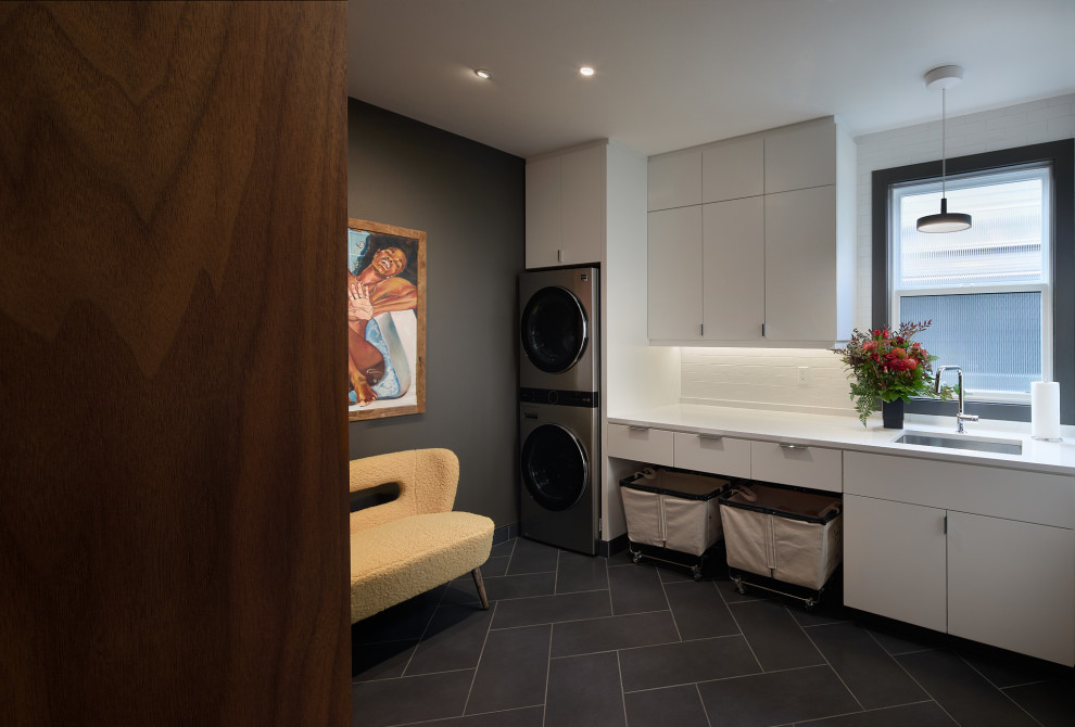 Design ideas for an expansive modern utility room in Seattle with an undermount sink, flat-panel cabinets, white cabinets, quartzite benchtops, white splashback, subway tile splashback, brown walls, porcelain floors, a stacked washer and dryer, grey floor and white benchtop.