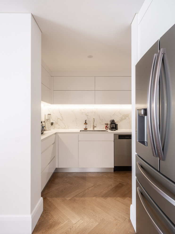Inspiration for a small contemporary l-shaped kitchen pantry in Sydney with a single-bowl sink, flat-panel cabinets, white cabinets, white splashback, engineered quartz splashback, stainless steel appliances, painted wood floors, with island and beige floor.