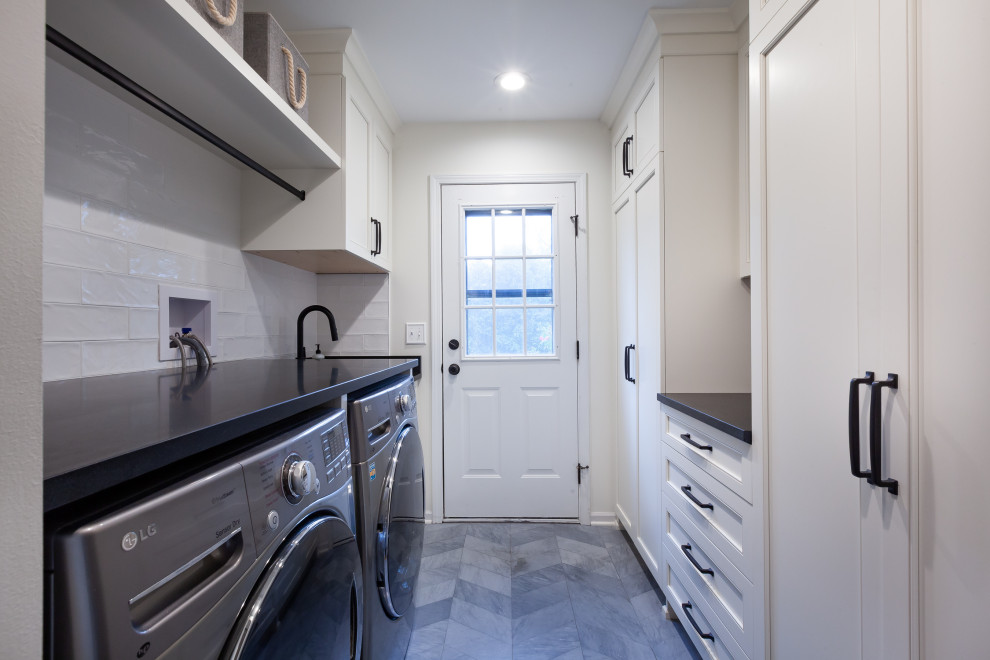 This is an example of a mid-sized country galley dedicated laundry room in Chicago with an undermount sink, beaded inset cabinets, white cabinets, granite benchtops, white splashback, porcelain splashback, white walls, slate floors, a side-by-side washer and dryer, grey floor and black benchtop.