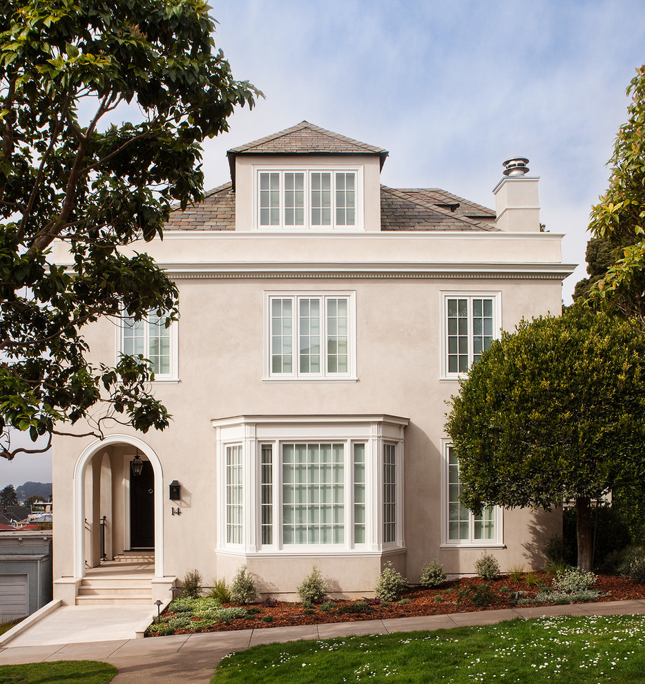 This is an example of a large traditional three-storey stucco beige exterior in San Francisco with a hip roof.