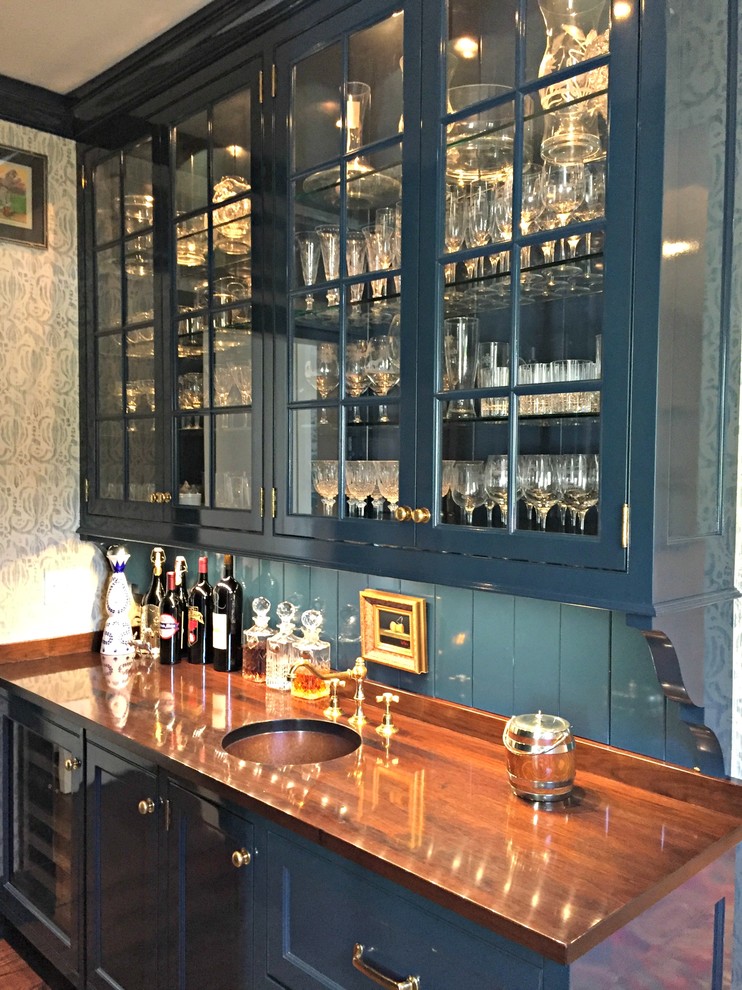 Photo of a mid-sized traditional single-wall wet bar in Cincinnati with an undermount sink, glass-front cabinets, blue cabinets, wood benchtops, blue splashback, dark hardwood floors and brown benchtop.