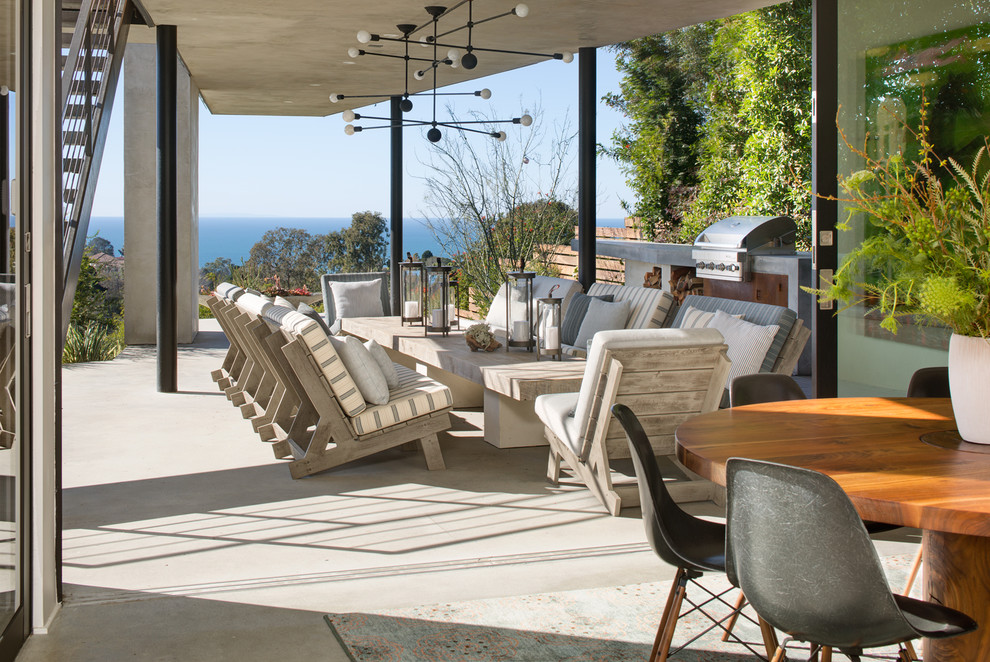 Example of a large minimalist backyard concrete patio design in San Diego with a roof extension