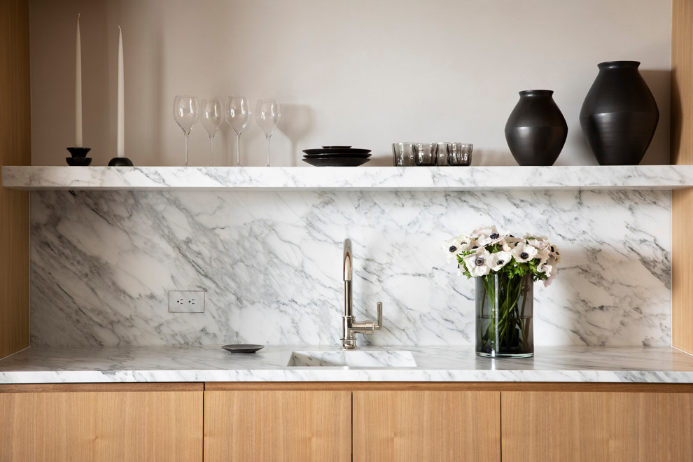 Inspiration for a small modern home bar in San Francisco with an undermount sink, light wood cabinets, marble benchtops, white splashback, stone slab splashback and white benchtop.