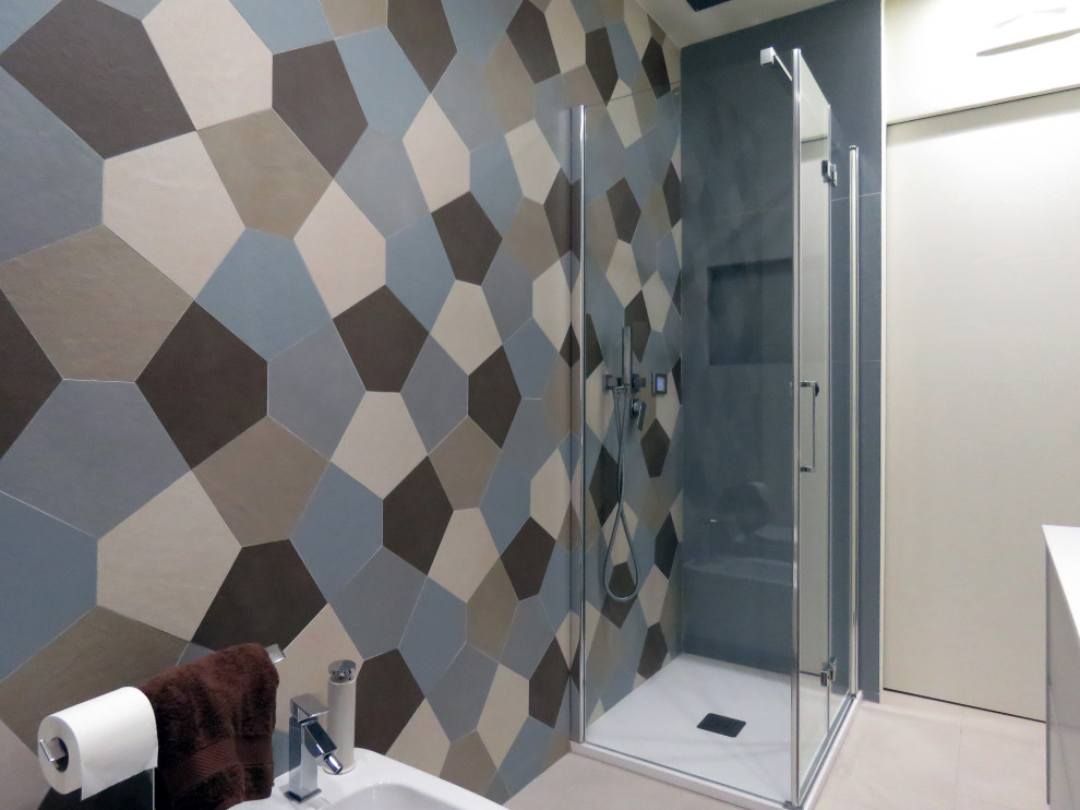 Mid-sized contemporary 3/4 bathroom in Catania-Palermo with flat-panel cabinets, white cabinets, a wall-mount toilet, multi-coloured tile, ceramic tile, beige walls, porcelain floors, an integrated sink, solid surface benchtops, beige floor, a hinged shower door and white benchtops.