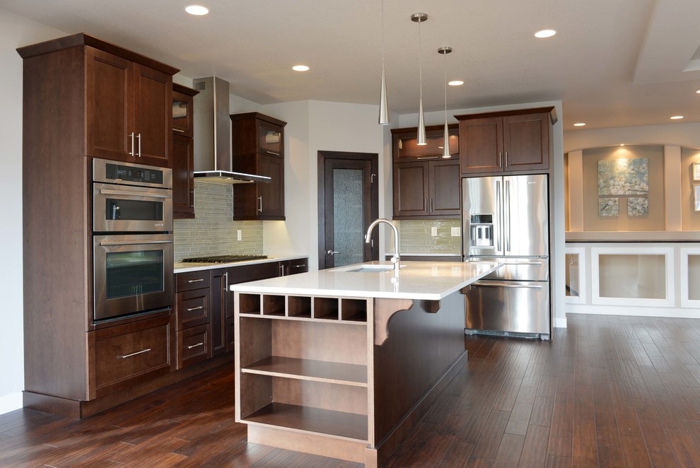 Eat-in kitchen - large transitional l-shaped dark wood floor and brown floor eat-in kitchen idea with an undermount sink, flat-panel cabinets, dark wood cabinets, quartz countertops, gray backsplash, glass sheet backsplash, stainless steel appliances and an island
