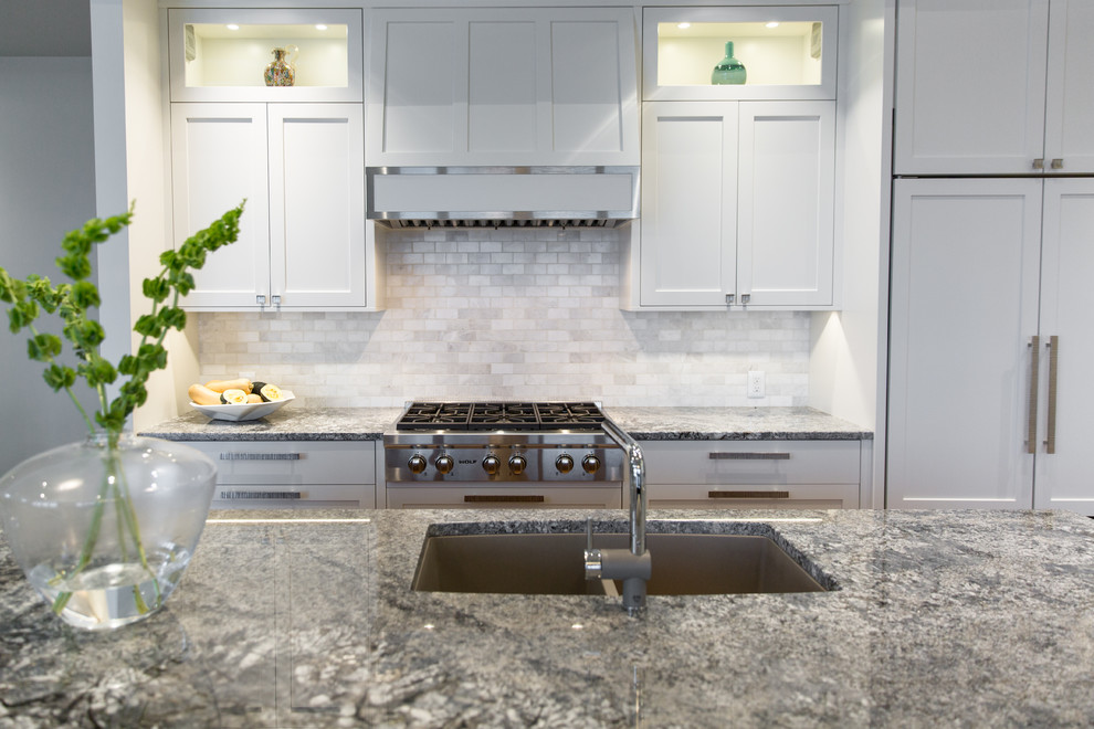 Inspiration for a mid-sized transitional l-shaped medium tone wood floor eat-in kitchen remodel in Vancouver with an undermount sink, shaker cabinets, white cabinets, granite countertops, white backsplash, white appliances and an island