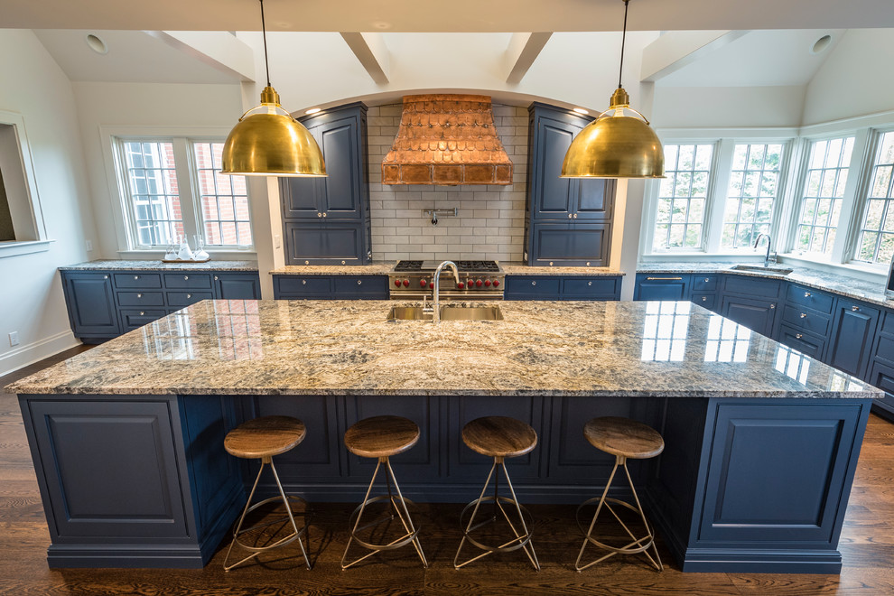 Inspiration for a large country l-shaped kitchen pantry in Cincinnati with a double-bowl sink, raised-panel cabinets, blue cabinets, granite benchtops, grey splashback, subway tile splashback, stainless steel appliances, medium hardwood floors, with island and brown floor.