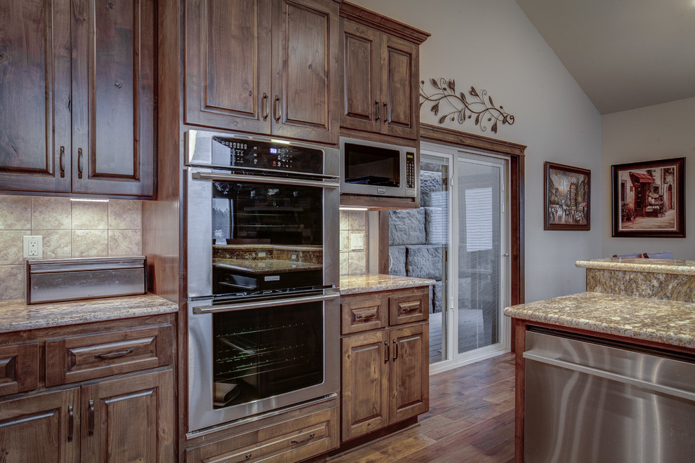 Large mountain style u-shaped medium tone wood floor eat-in kitchen photo in Seattle with an undermount sink, raised-panel cabinets, medium tone wood cabinets, granite countertops, beige backsplash, ceramic backsplash, stainless steel appliances and an island