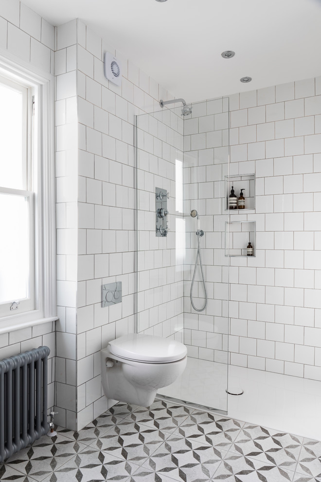 Photo of a mid-sized contemporary bathroom in London with a wall-mount toilet, white tile, ceramic tile, white walls, ceramic floors, an open shower and an open shower.