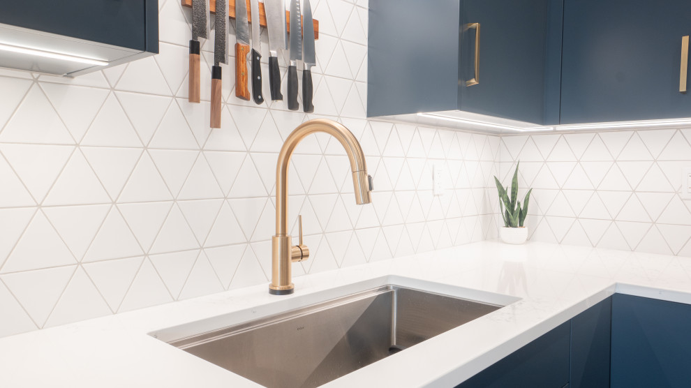 Open concept kitchen - modern l-shaped vinyl floor and beige floor open concept kitchen idea in Toronto with an undermount sink, flat-panel cabinets, blue cabinets, quartz countertops, white backsplash, ceramic backsplash, stainless steel appliances, an island and white countertops