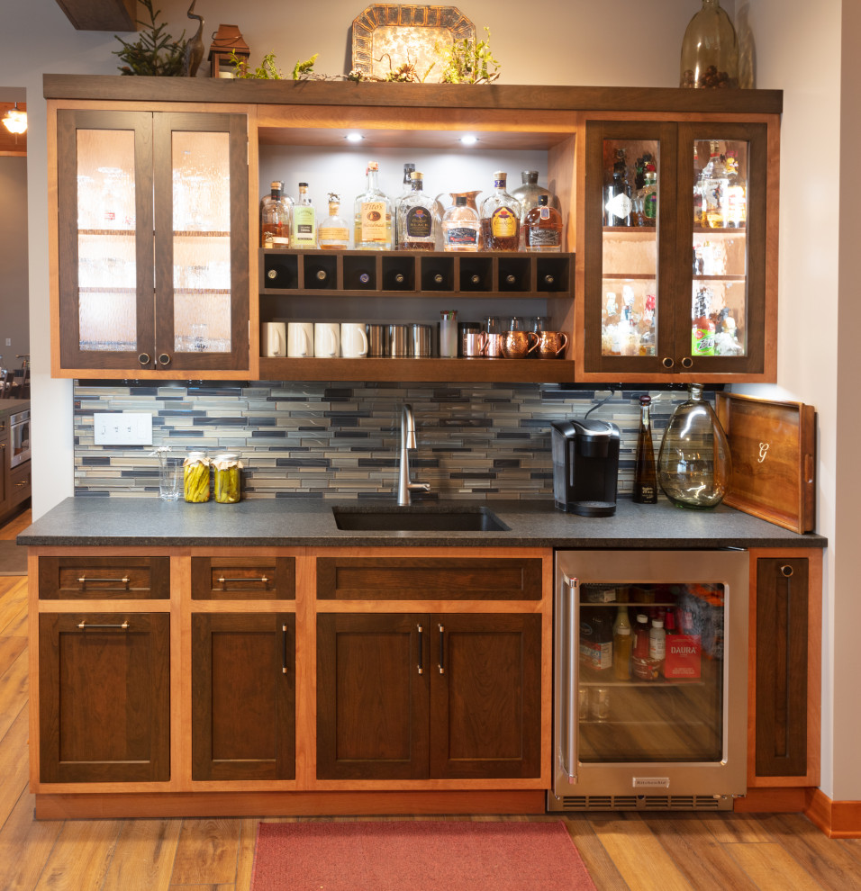 Small country single-wall wet bar in Other with an undermount sink, shaker cabinets, medium wood cabinets, granite benchtops, multi-coloured splashback and glass tile splashback.