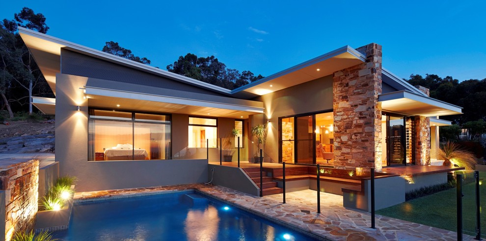 This is an example of a mid-sized midcentury front yard rectangular pool in Perth with natural stone pavers.