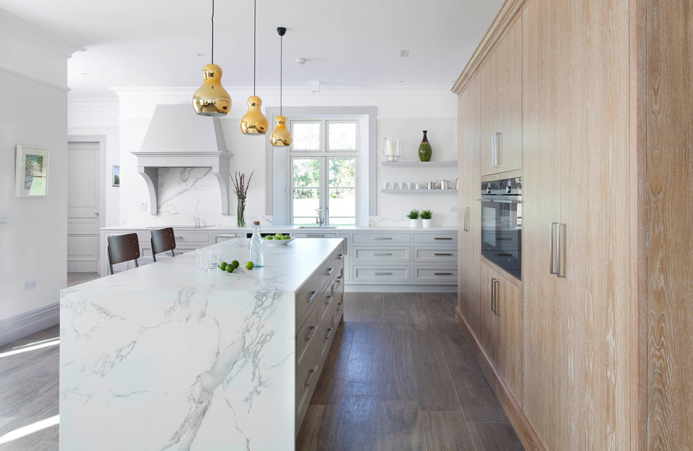 Design ideas for a large contemporary u-shaped open plan kitchen in Other with an undermount sink, raised-panel cabinets, grey cabinets, quartz benchtops, white splashback, stone slab splashback, black appliances, porcelain floors, with island and brown floor.