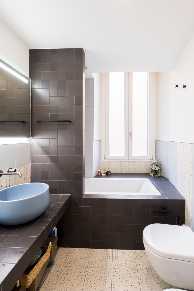 Пример оригинального дизайна: маленькая главная ванная комната в современном стиле с накладной ванной, душем над ванной, раздельным унитазом, разноцветной плиткой, керамогранитной плиткой, разноцветными стенами, полом из керамогранита, настольной раковиной, столешницей из плитки, разноцветным полом, открытым душем, черной столешницей, тумбой под одну раковину и многоуровневым потолком для на участке и в саду