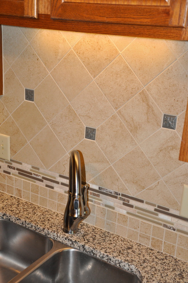 Example of a small transitional u-shaped linoleum floor enclosed kitchen design in Cincinnati with an undermount sink, recessed-panel cabinets, medium tone wood cabinets, granite countertops, beige backsplash, stone tile backsplash, stainless steel appliances and orange walls