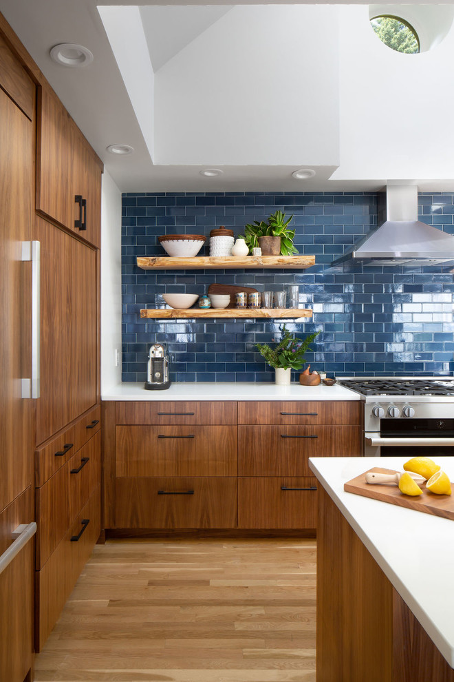 Open concept kitchen - large transitional u-shaped medium tone wood floor and brown floor open concept kitchen idea in Seattle with an undermount sink, flat-panel cabinets, medium tone wood cabinets, quartz countertops, blue backsplash, ceramic backsplash, stainless steel appliances, an island and white countertops