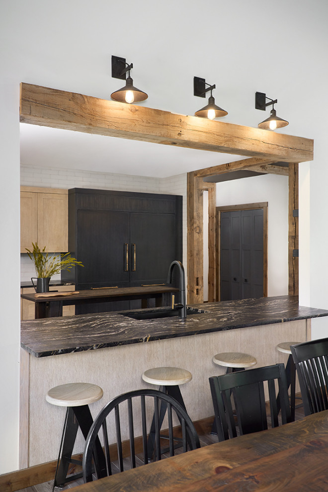 This is an example of a large country eat-in kitchen in Grand Rapids with an undermount sink, granite benchtops, subway tile splashback, panelled appliances, with island, black floor, black benchtop, recessed-panel cabinets, light wood cabinets and white splashback.