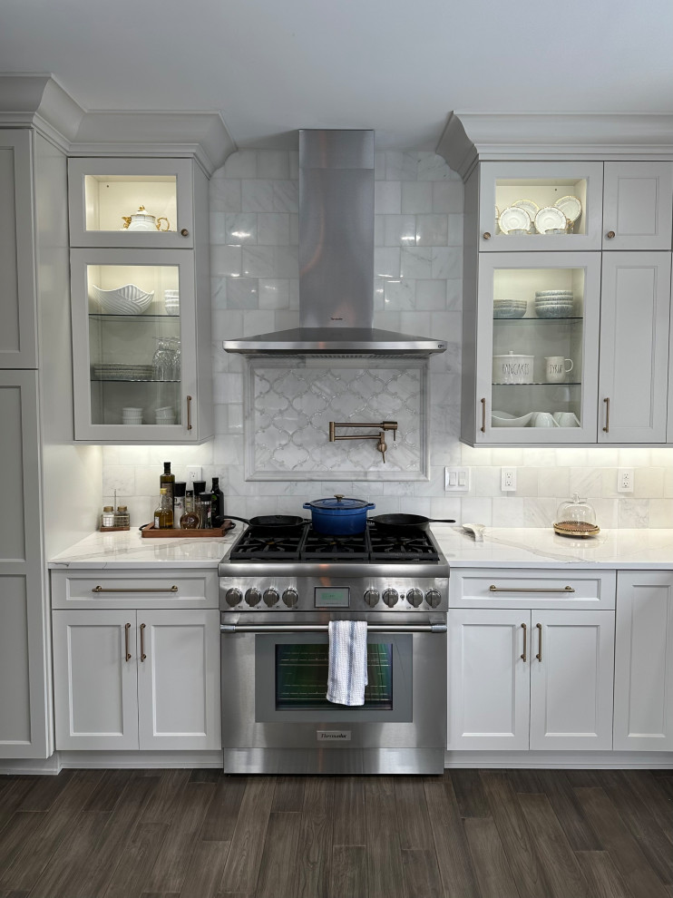 Large transitional u-shaped eat-in kitchen in Detroit with an undermount sink, shaker cabinets, white cabinets, copper benchtops, white splashback, stainless steel appliances, with island and white benchtop.