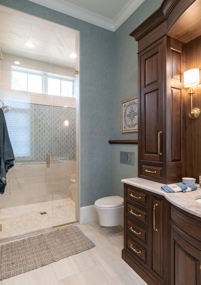 Photo of a mid-sized master bathroom in Grand Rapids with beaded inset cabinets, brown cabinets, an alcove shower, a wall-mount toilet, blue tile, porcelain tile, blue walls, cement tiles, an undermount sink, engineered quartz benchtops, beige floor, a hinged shower door, beige benchtops, a shower seat, a single vanity, a built-in vanity and wallpaper.