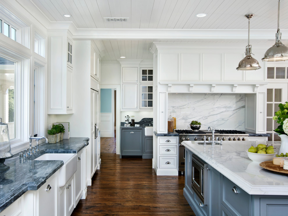 Photo of a large contemporary l-shaped kitchen in San Francisco with a farmhouse sink, beaded inset cabinets, white cabinets, marble benchtops, white splashback, dark hardwood floors, with island, stone slab splashback, brown floor and panelled appliances.