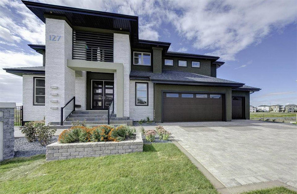 Photo of an expansive modern two-storey stucco grey house exterior in Other with a hip roof and a shingle roof.